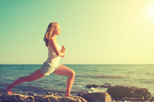 young woman doing yoga on coast of sea on beach